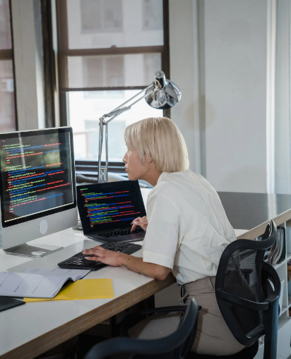 Women coding on PC with additional screen